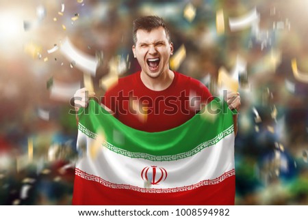 Iranian fan, a fan of a man holding the national flag of Iran in his hands. Soccer fan in the stadium.