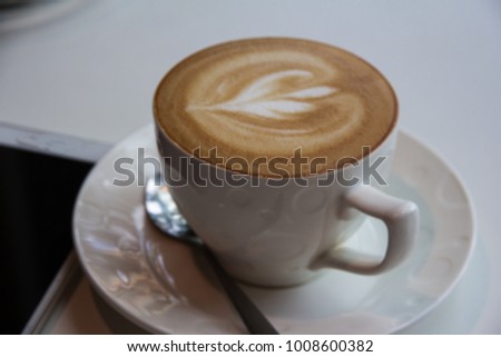 In selective of heart picture from cream foam of cuppuccino coffee cup put on table and coffee shop,blurry light around.