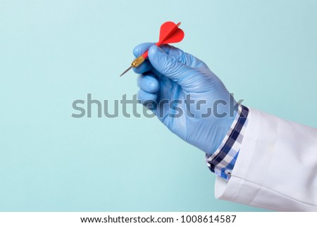Doctor in a glove holds a red dart. Copy space for text Royalty-Free Stock Photo #1008614587