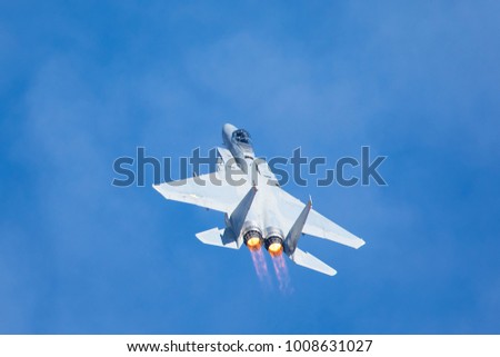 F-15 Eagle in a very close view, with afterburners on and clouds in the background