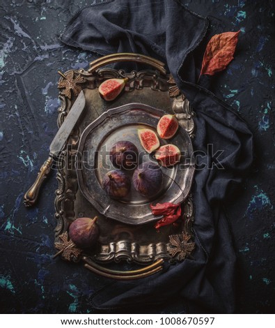 Fresh organic figs on an antique vintage plate and a tray, an old knife on a dark blue concrete background. View from above
