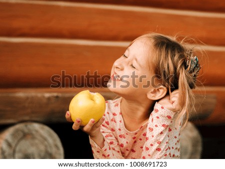 Fun and childhood. The little girl is holding a yellow bulk apple. Summer life. bright holidays in the country. Close the eyes of pleasure.