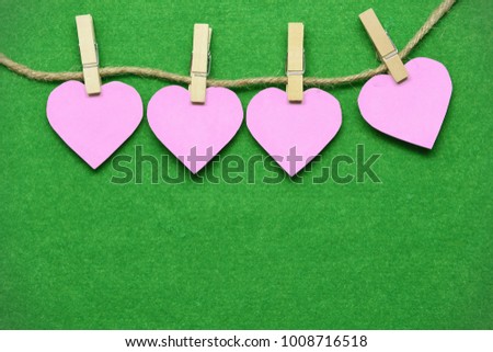 Pink hearts that are clamping the wood clamp.Hanging on to the grass green moist.