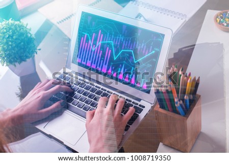 Hand using laptop with business chart on screen placed on office desk with objects. Finance, report and success concept. Double exposure 