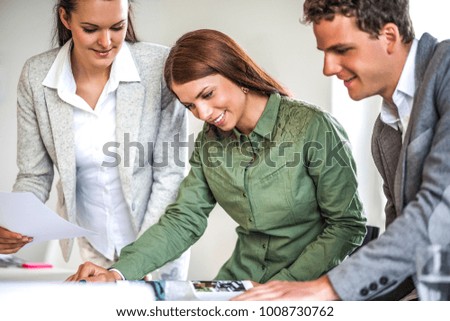 Young businesswoman with colleagues working at desk in office
