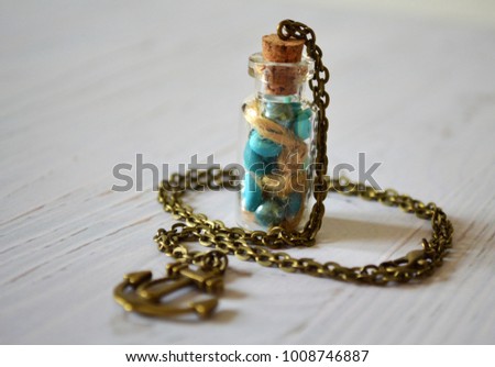 Bottle pendant with shells and pearls on white wooden background