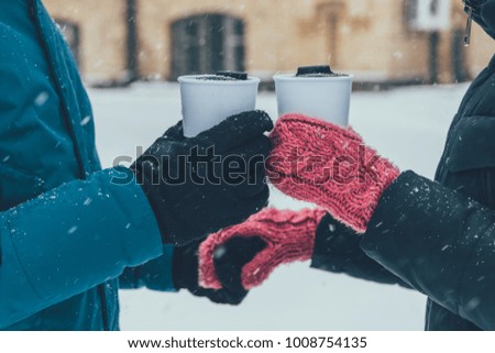 partial view of couple with hot drinks holding hands on street in winter