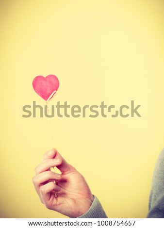 Symbolism love romance concept. Heart on wooden stick. Symbol  of affection on pole held by human arm. 