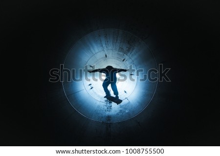 Man skateboarding inside a dark tunnel