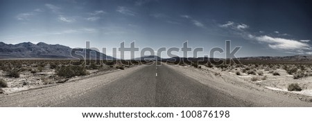 A barren stretch of asphalt extends into the vast wilderness of Death Valley National Park.