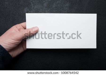 Male hands holding a DL Flyer Mock-Up on a black background.