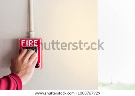 Hand pulling down the fire alarm button.