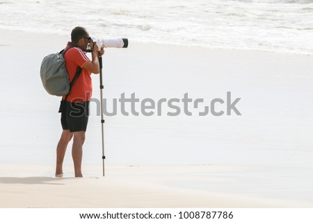 photographer on the beach with a professional camera and a monopod stand