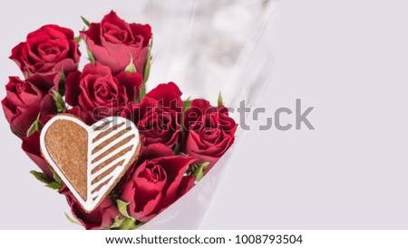 Bouquet of red roses and sweet heart for good luck. Elegant floral Valentine's background with ornate gingerbread. Mother's Day, Women's Day, birthday, wedding.