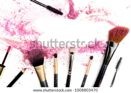 Traces of vibrant pink powder and blush forming a frame, with makeup brushes and lip gloss. A template for a makeup artist's business card or flyer design, with copy space