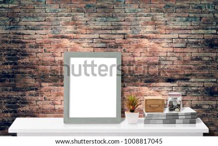 Mock up: Workspace desk with picture frame,books, and glass jar with coins,white desk with copy space with old brick wall for products display