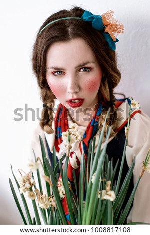 Fashionable beautiful brunette happy girl in a jumpsuit with floral embroidery with color makeup: red cheeks and lips. Granny chic style. Retouched portrait.Conceptual photo of country style