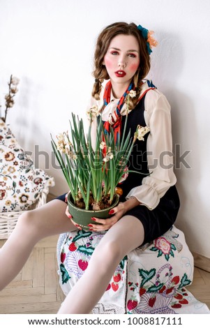 Fashionable beautiful brunette happy girl in a jumpsuit with floral embroidery with color makeup: red cheeks and lips. Granny chic style. Retouched portrait.Conceptual photo of country style