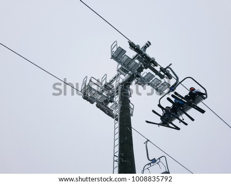 
Three skiers climb the funicular in the mountains, Turkey, Uludag. 
Construction of cable car lift in winter on a white snow background.