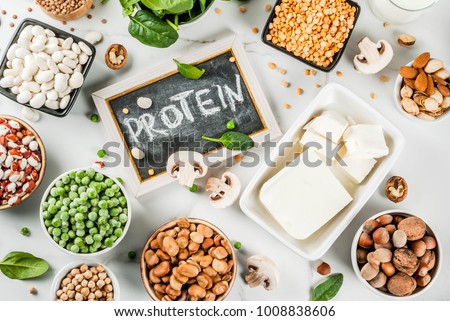 Healthy diet vegan food, veggie protein sources: Tofu, vegan milk, beans, lentils, nuts, soy milk, spinach and seeds. Top view on white table. Royalty-Free Stock Photo #1008838606