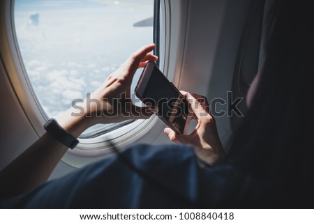 Close up woman hand holding mobile phone and take a photo outside airplane window