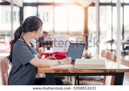Concentrated doctor or nurse working on line with a laptop sitting in a desk in a consultation Royalty-Free Stock Photo #1008852631