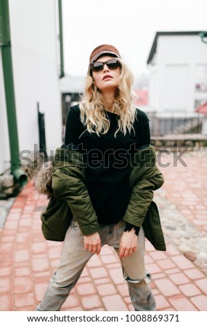 Fashionable young girl model in trendy famous italian jeans and white old fashioned expensive sneakers posing for camera. European beautiful woman stylish look. Well dressed woman. Modern appearance.