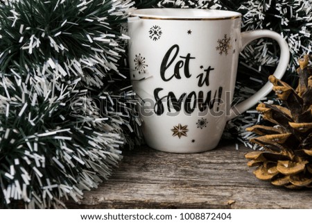 Winter cup "Let it Snow" on the background of a tree, a tree and a pine cone