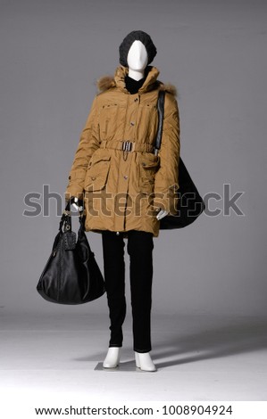 Full length female mannequin dressed in trousers ,hat, with coat, handbag on light background


