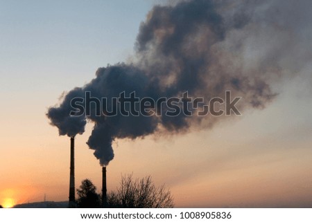 Smoke from industrial chimneys (pipes) against the sunrise (sunset) sky. Air Pollution. Global warming.