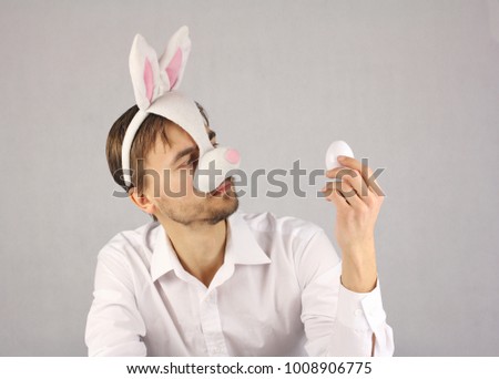 man in the mask Easter Bunny and white shirt looking at the Easter egg 