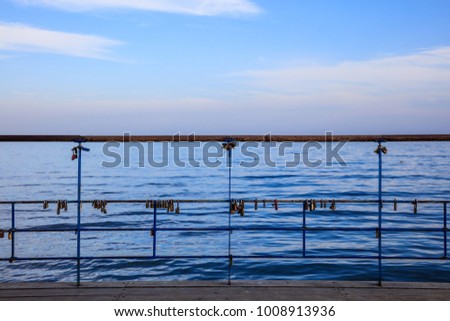 Rusty padlocks locks on peeled railing. Tradition for couple in love. Blue sky and sea backdrop.