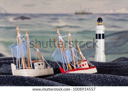 View of toys, fishing boats on a spotted fabric material. Old school-painting as background, beacon.