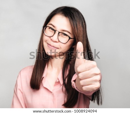 Young asian woman with long hair, wearing pink shirt and glasses make 
Gesture with hand, Selective focus