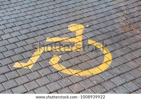 Post with disabled parking space and sign in front of parking bay in car park / Marked parking for people with special needs / Handicapped symbol, sign on asphalt, painted detail of road and street.