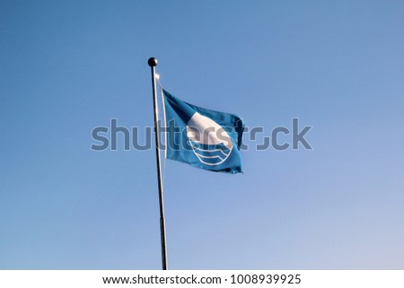 Detail of blue flag beach quality award flag flying, which means it has reached specific standards on water quality, safety, services, environmental management and information.