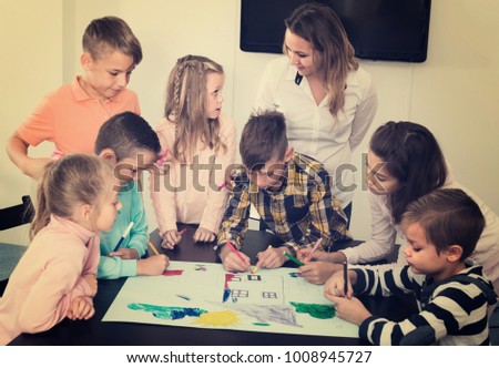 Professor and elementary age children drawing and studying together 