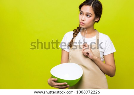 Young housewife holding a bowl and a Eggbeater.