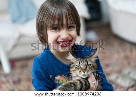 Little boy playing with his cat enjoying at home