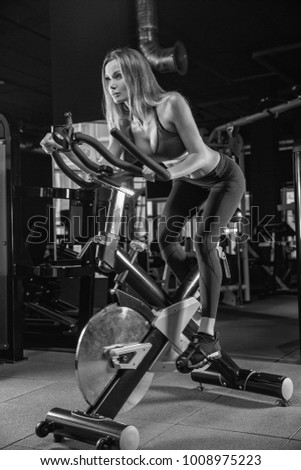 The girl is engaged in an exercise bike, personal training in the gym.