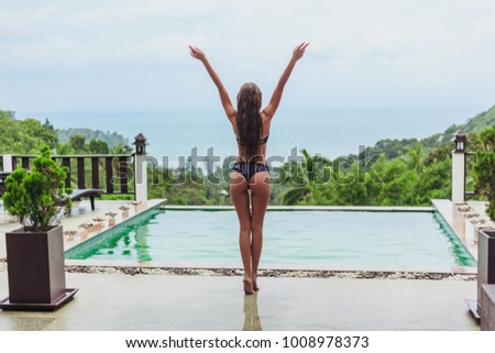 back view of girl posing at swimming pool on tropical resort