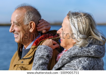 Portrait of happy senior couple by the lake on sunny autumn day.