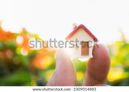 Hand holding miniature house using as property, family and business goal concept