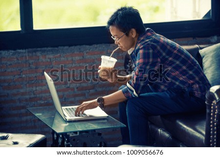 Business woman searching job with a laptop, through a window sitting on a sofa in the coffee shop with a warm light.