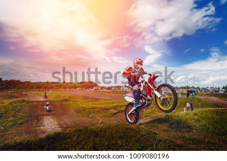 Racer on dirtbike motorcycle jumps and takes off over the track, in background the opponent is catching up. Concept primacy, rivalry, competition, extreme