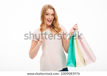 Picture of cheerful young woman looking camera isolated over white background holding credit card and shopping bags.