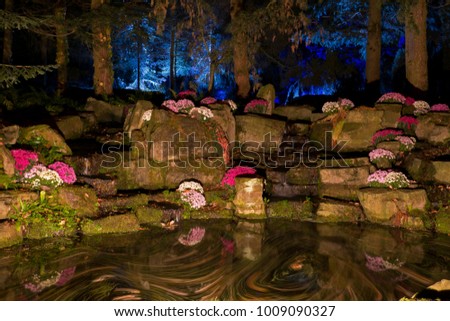 A rock walled pond by night, with moving water