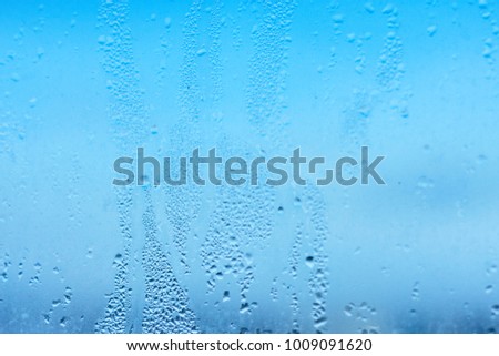Window glass with condensation, strong, high humidity in the room, large water droplets, cold tone
