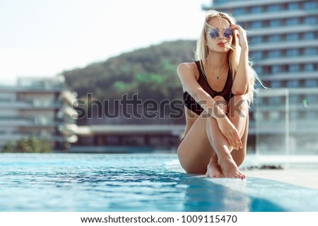 Young model girl in black bikini posing near pool