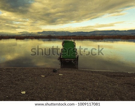 Old fishing wooden pier and river against the backdrop of mountains and colorful sunset. Meditative relaxing natural landscape